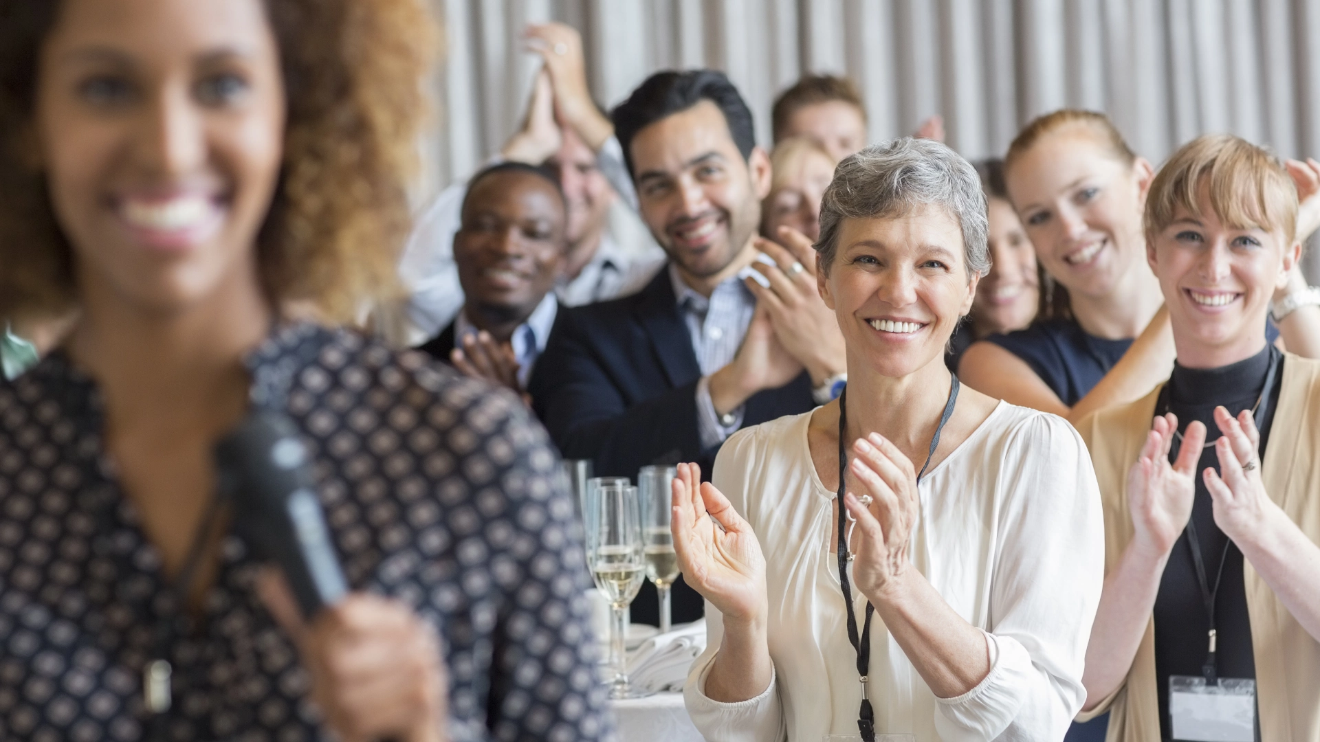 Smiling woman applauded by audience.